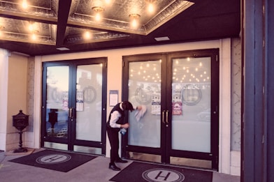 woman in white shirt standing near glass door