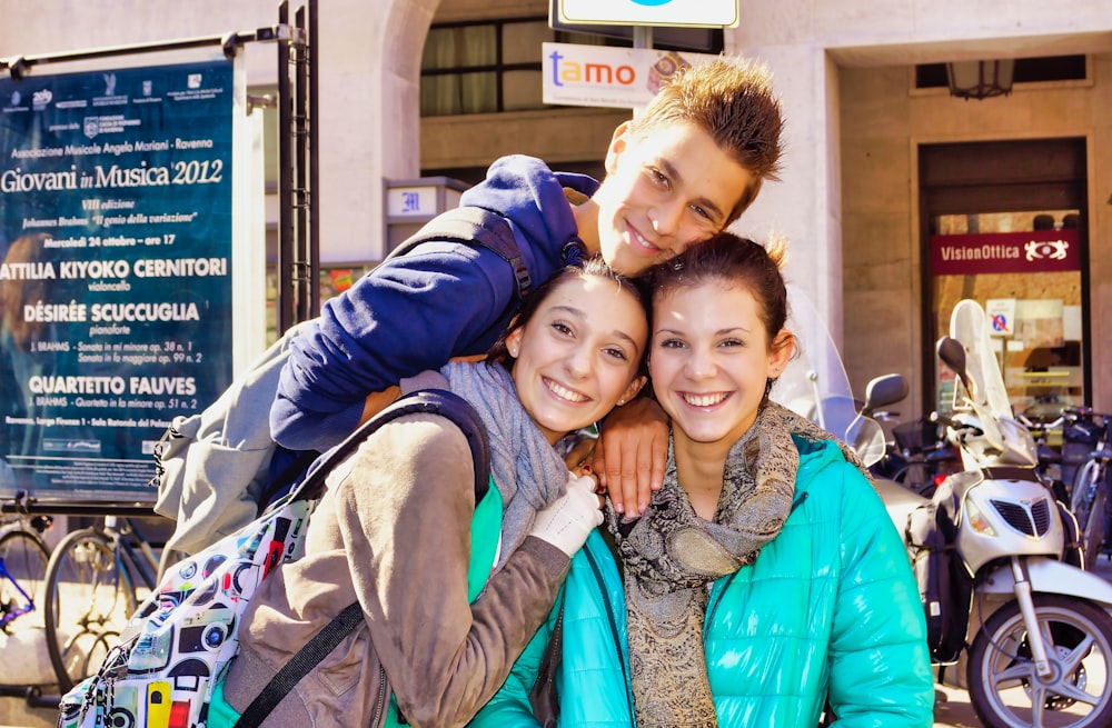 man in blue jacket hugging woman in gray scarf