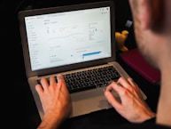 person using macbook pro on black table