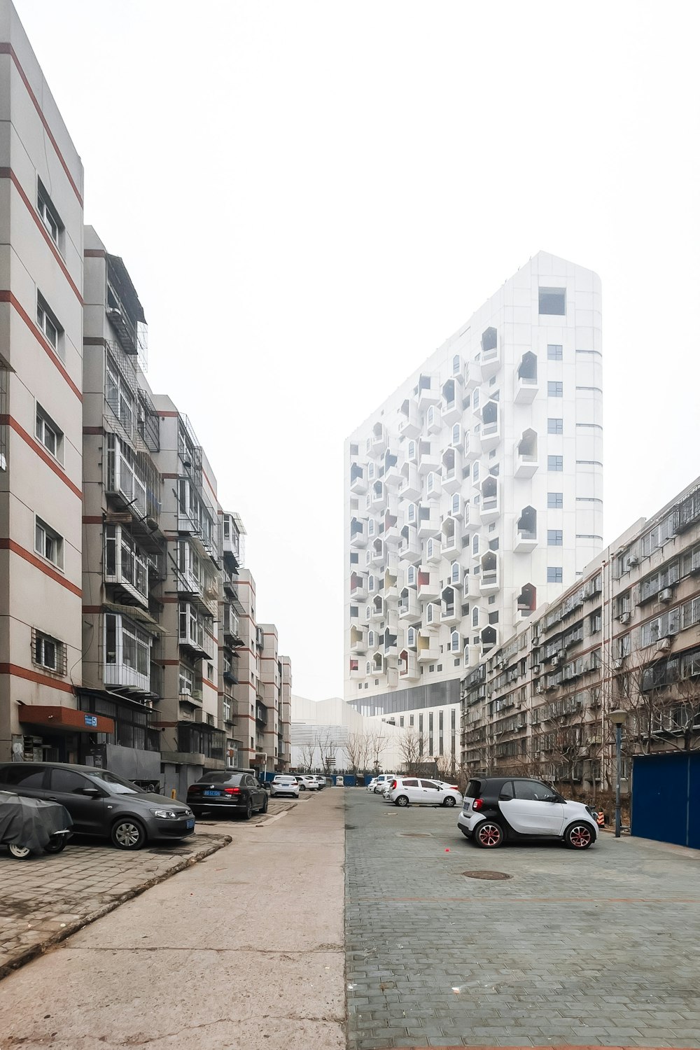 cars parked on side of the road in between high rise buildings during daytime