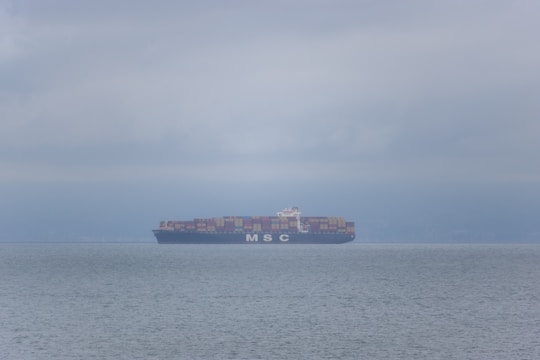 A large cargo ship navigating through calm waters with containers stacked high.
