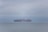 A cargo ship loaded with containers navigating through calm waters.