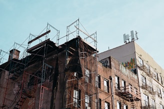 A fixer-upper brick townhouse in an up-and-coming neighborhood with scaffolding outside.