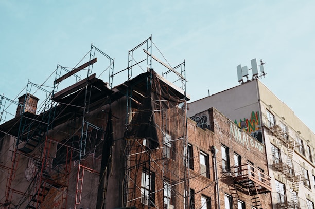 A fixer-upper brick townhouse in an up-and-coming neighborhood with scaffolding outside.
