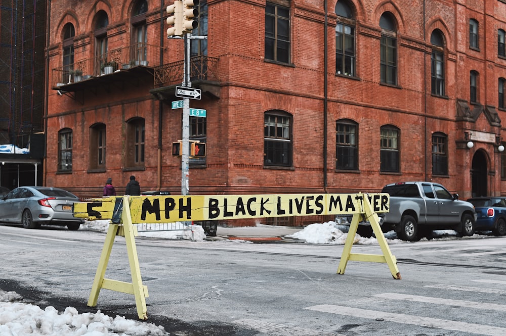 yellow and black metal stand on snow covered ground near brown concrete building during daytime