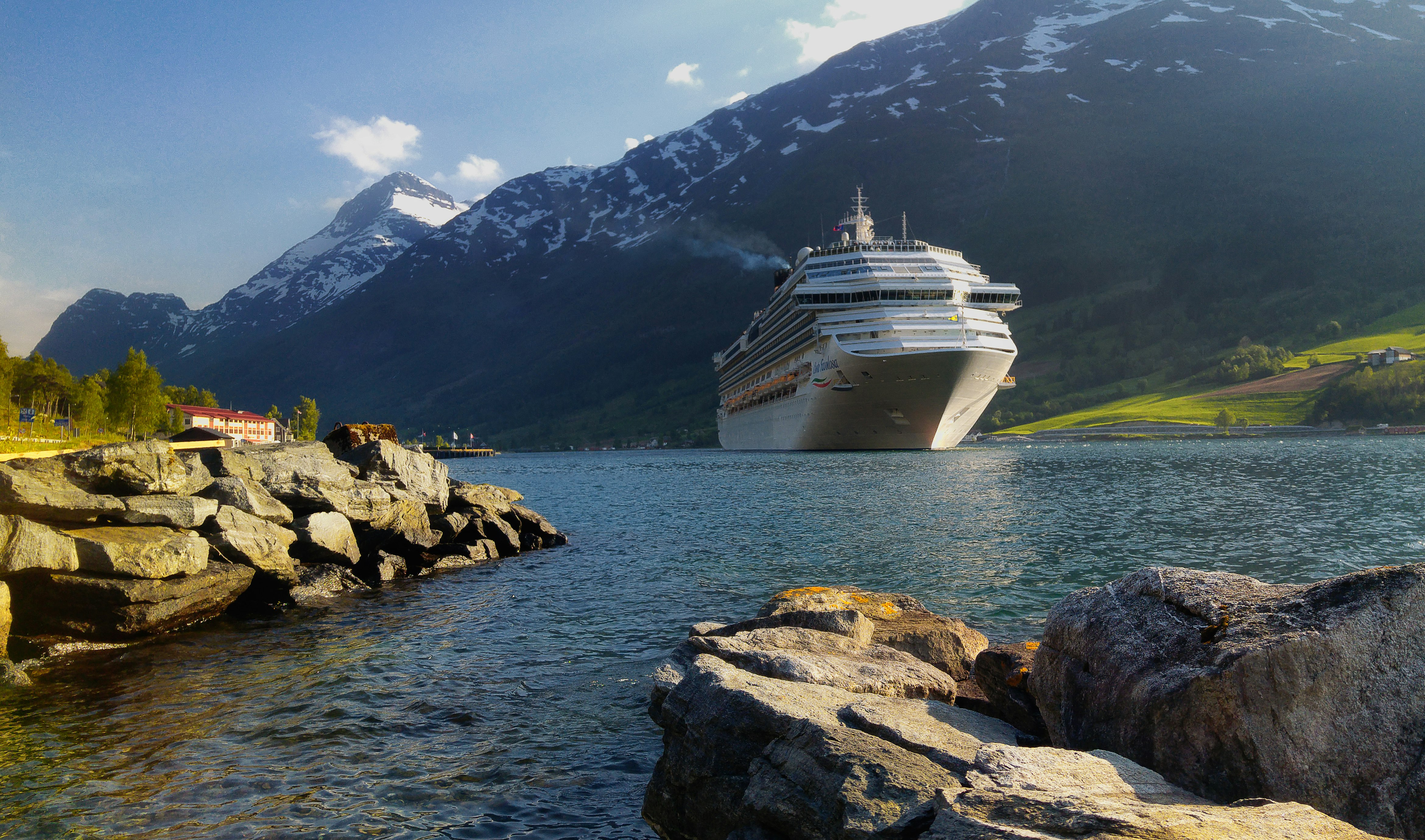 white cruise ship on water near rocky mountain during daytime