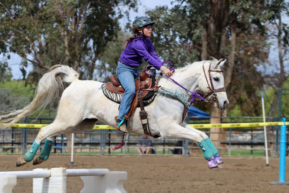 man in blue jacket riding white horse during daytime