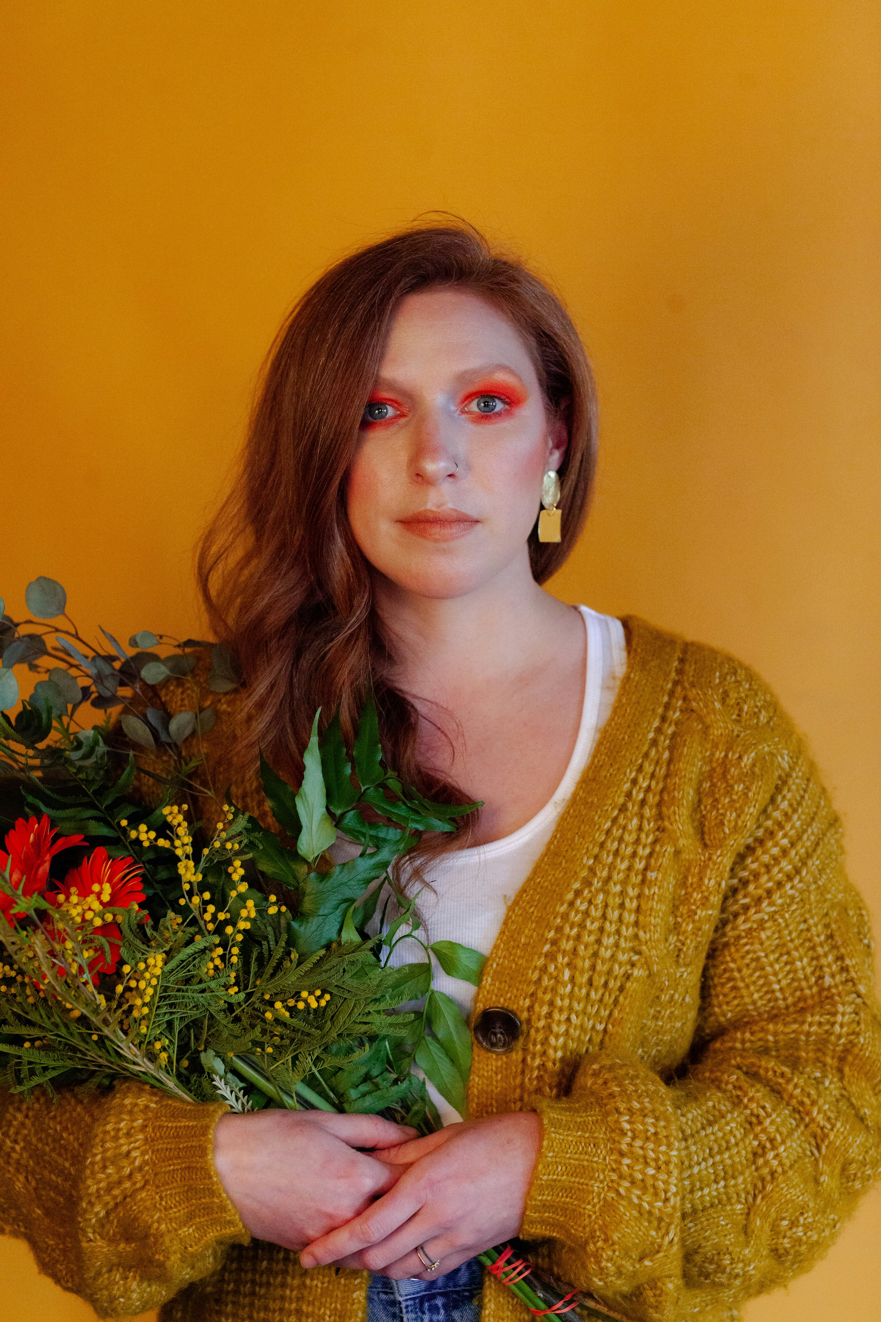 woman in yellow knit cardigan standing beside green plant