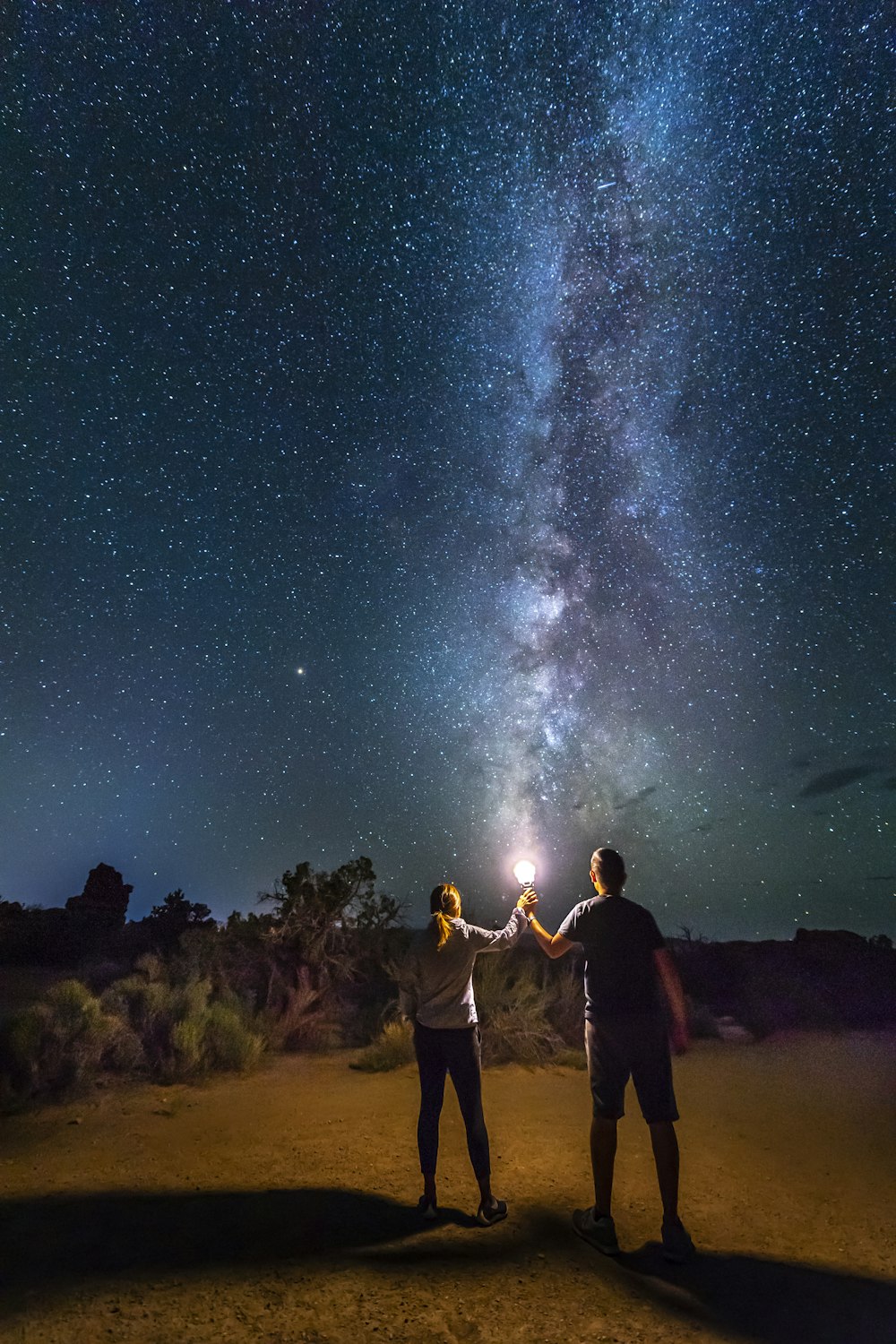 星空の下、茶色の砂の上に立つ人々