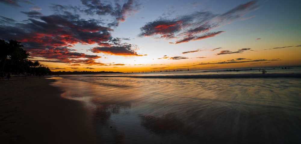 body of water under cloudy sky during sunset