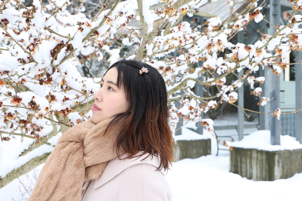 woman in white coat standing under white cherry blossom tree during daytime