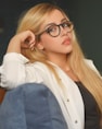 woman in white long sleeve shirt and blue denim jeans wearing black framed eyeglasses