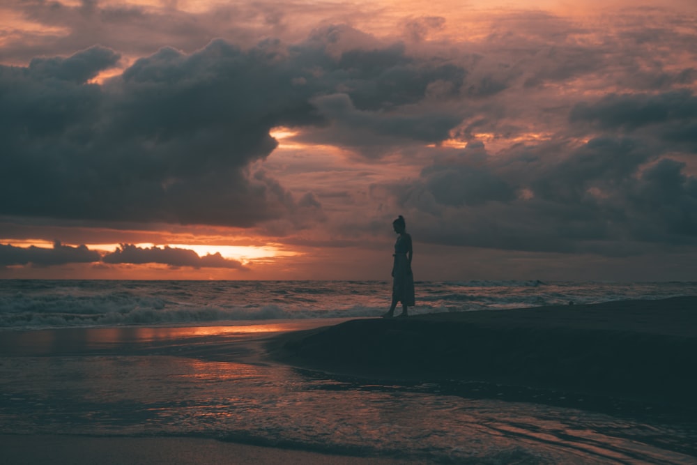 silhouette of man standing on beach during sunset