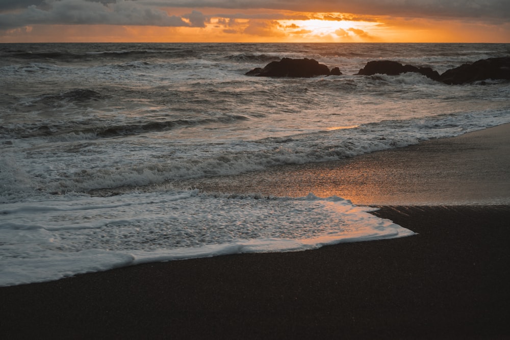 Meereswellen stürzen während des Sonnenuntergangs an Land