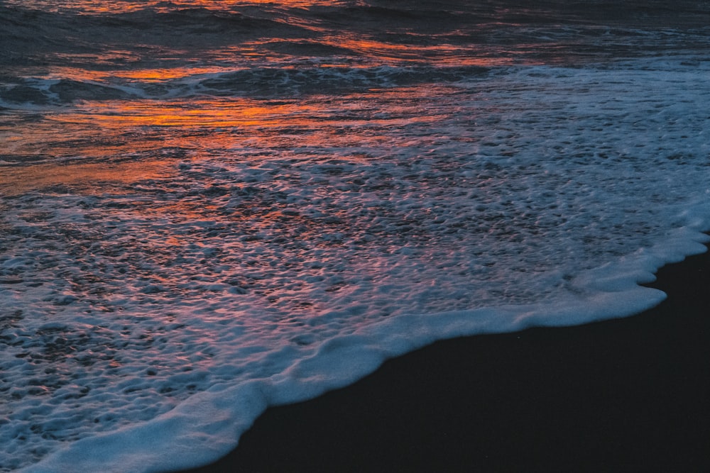 Olas del océano rompiendo en la costa durante la puesta de sol