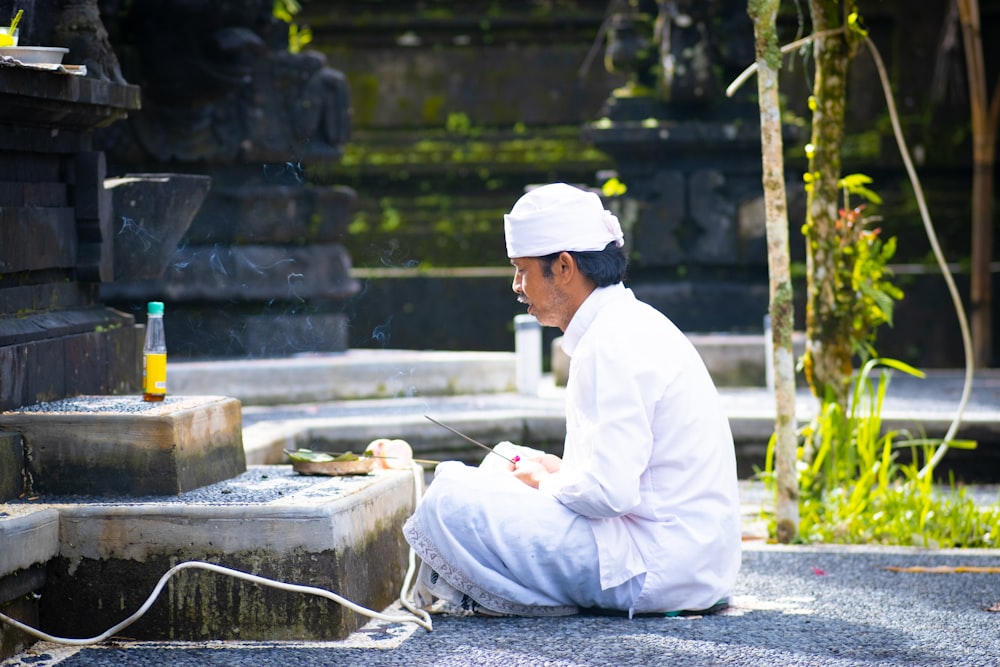 man in white thobe sitting on concrete bench during daytime