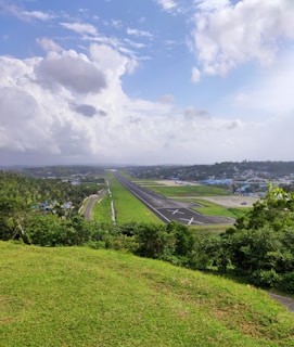 A scenic view of an airport runway surrounded by green fields and blue skies.