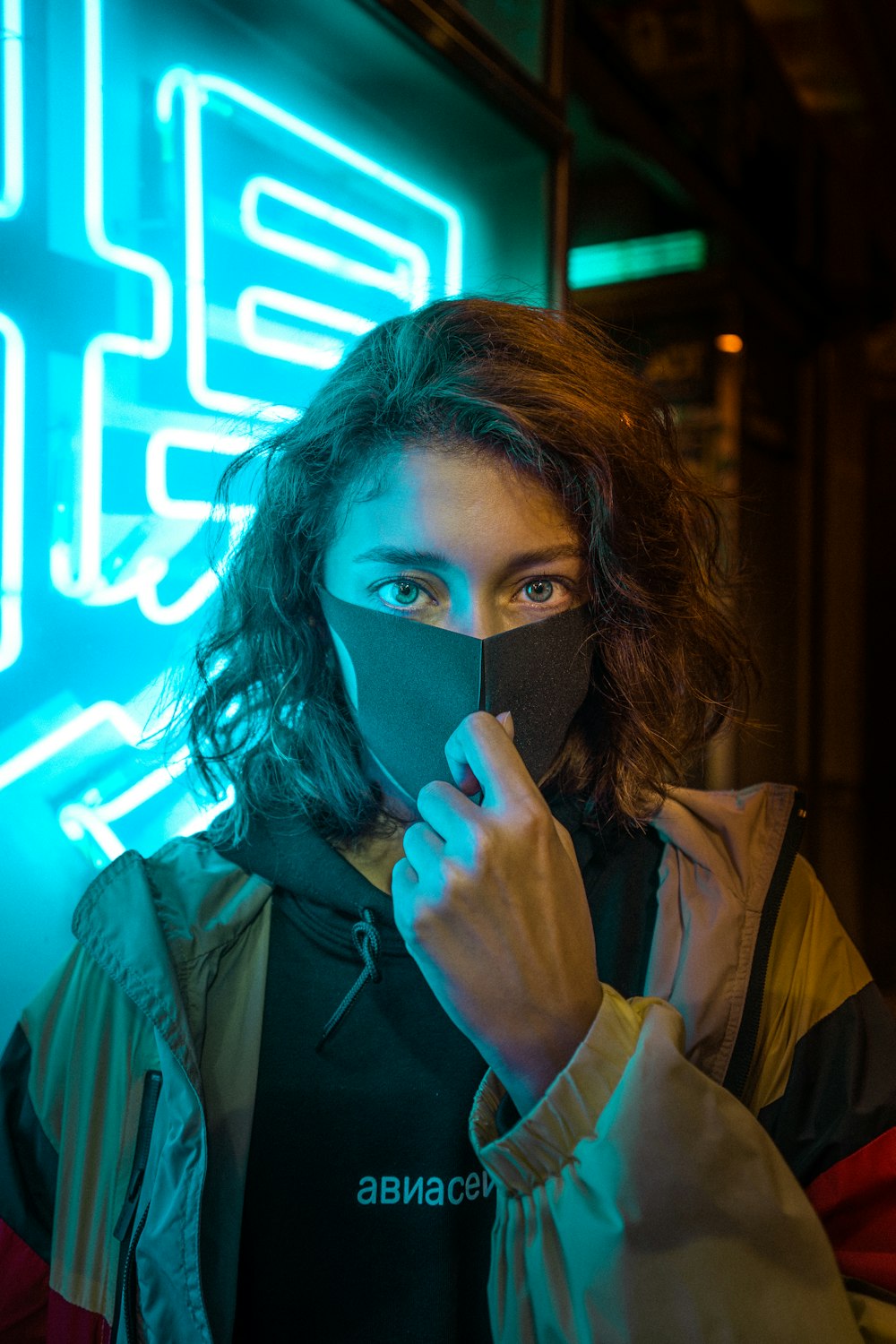 woman in brown coat covering her face with her black mask