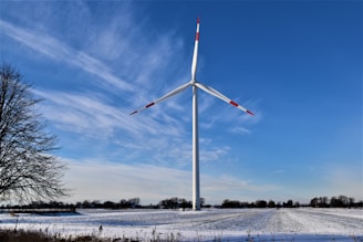 white wind turbine on snow covered ground under blue sky during daytime