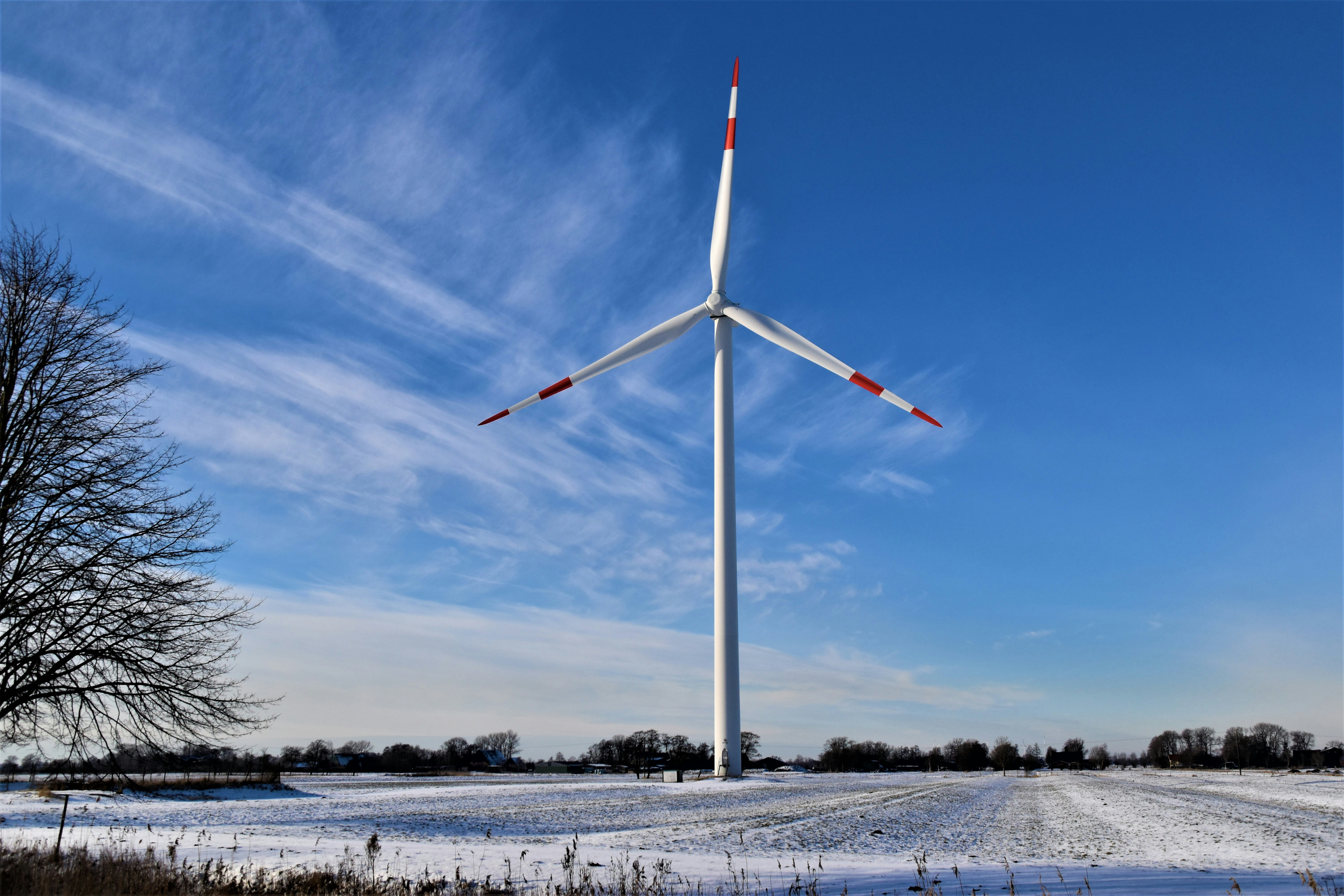 white wind turbine on snow covered ground under blue sky during daytime