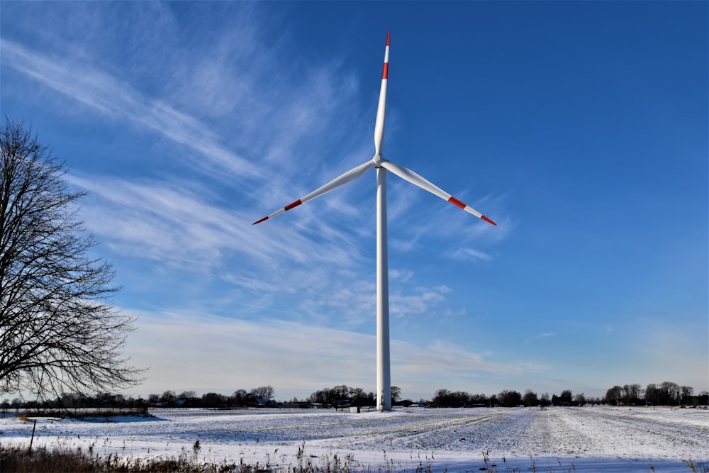 Turbina eolica bianca su terreno coperto di neve sotto cielo blu durante il giorno