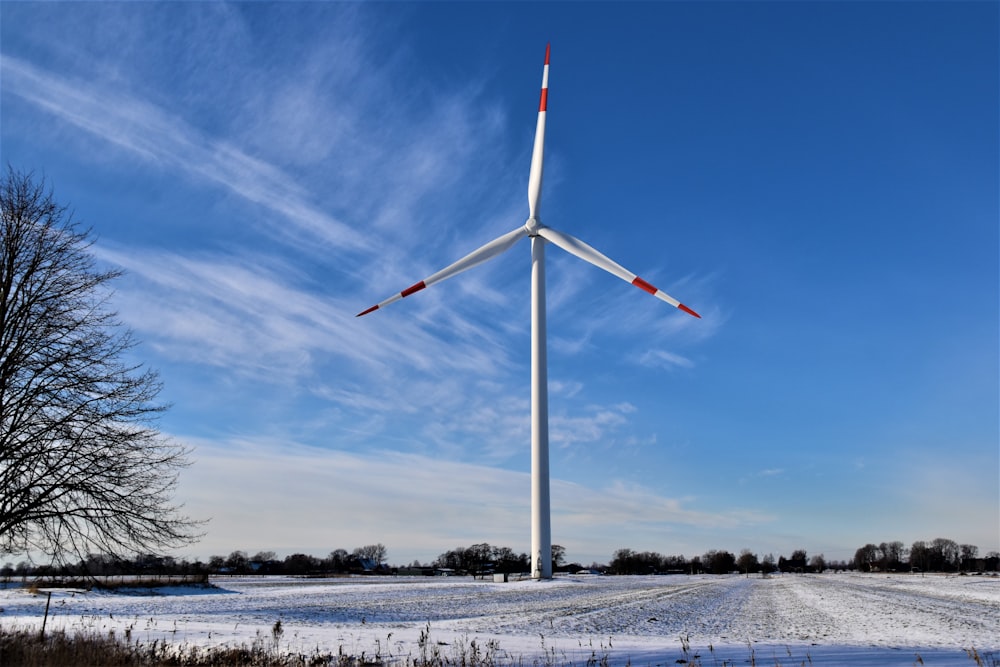 turbina eólica branca no solo coberto de neve sob o céu azul durante o dia
