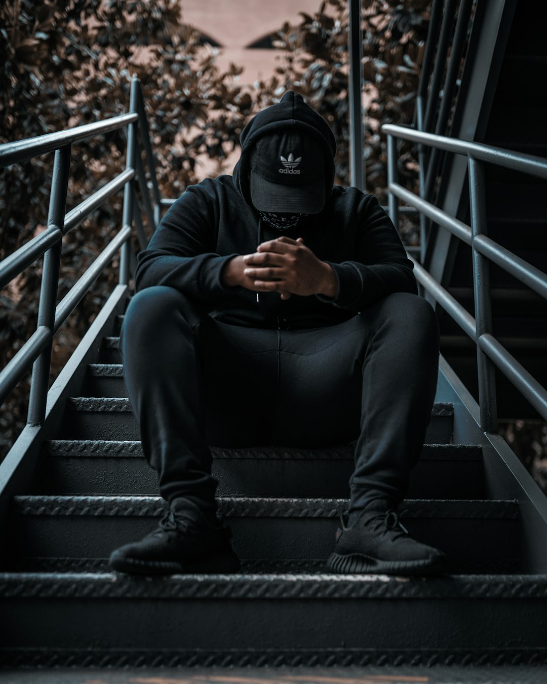 man in black jacket and black pants sitting on black staircase