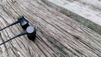 Compact and portable in-ear headphones displayed on a wooden surface.