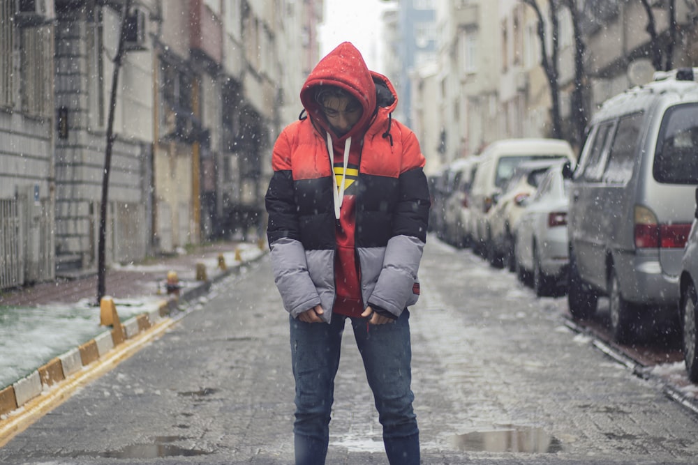 child in red hoodie and blue denim jeans walking on sidewalk during daytime