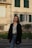woman in black coat standing near brown concrete building during daytime