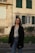 woman in black coat standing near brown concrete building during daytime