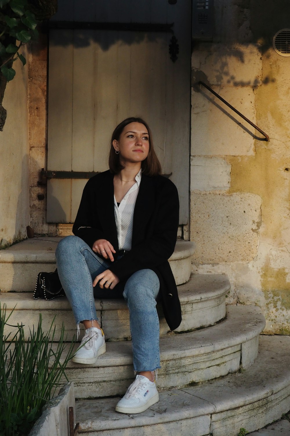 woman in black blazer sitting on gray concrete bench