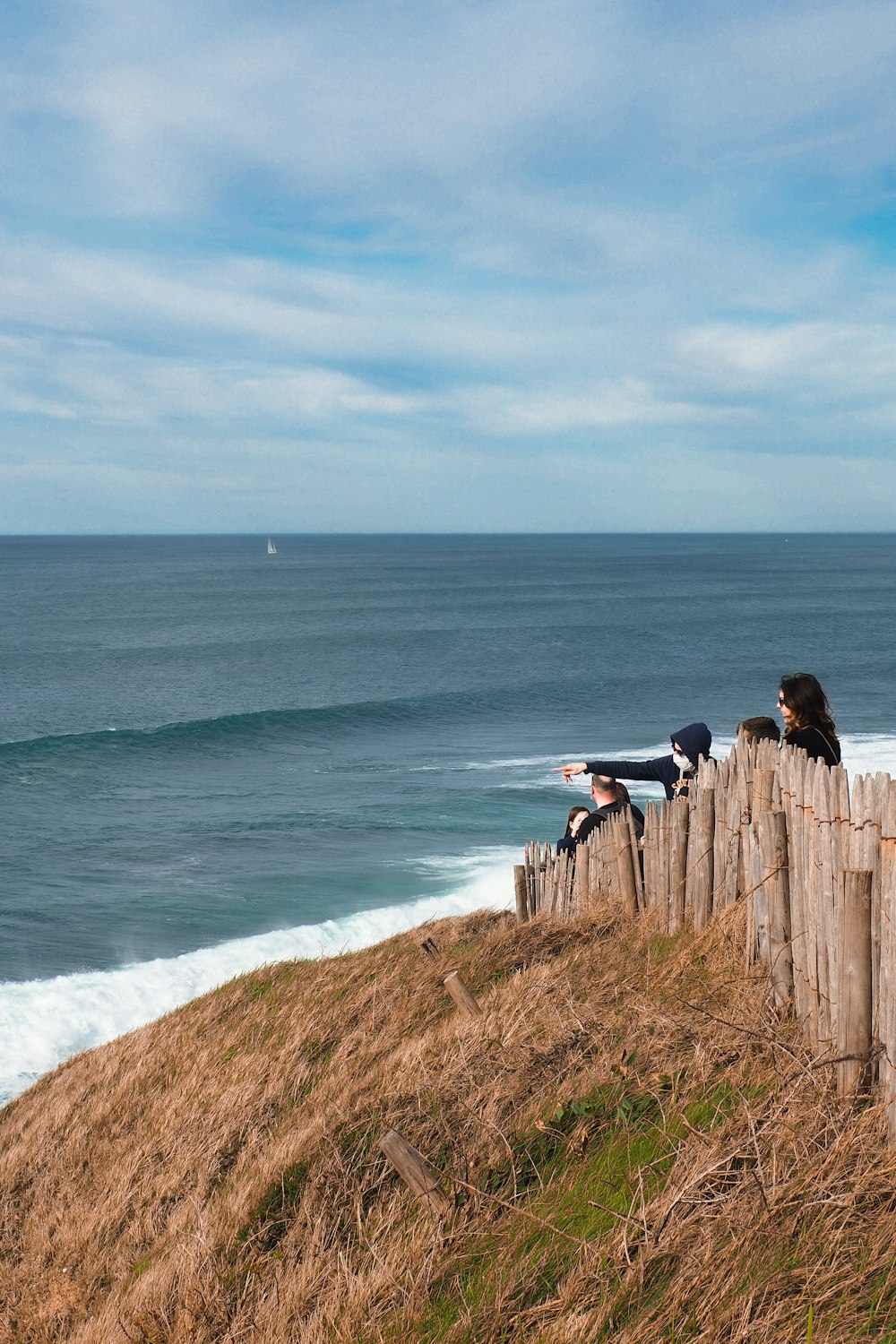 people standing on brown rock formation near sea during daytime