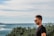 man in black crew neck t-shirt standing near green plants and body of water during