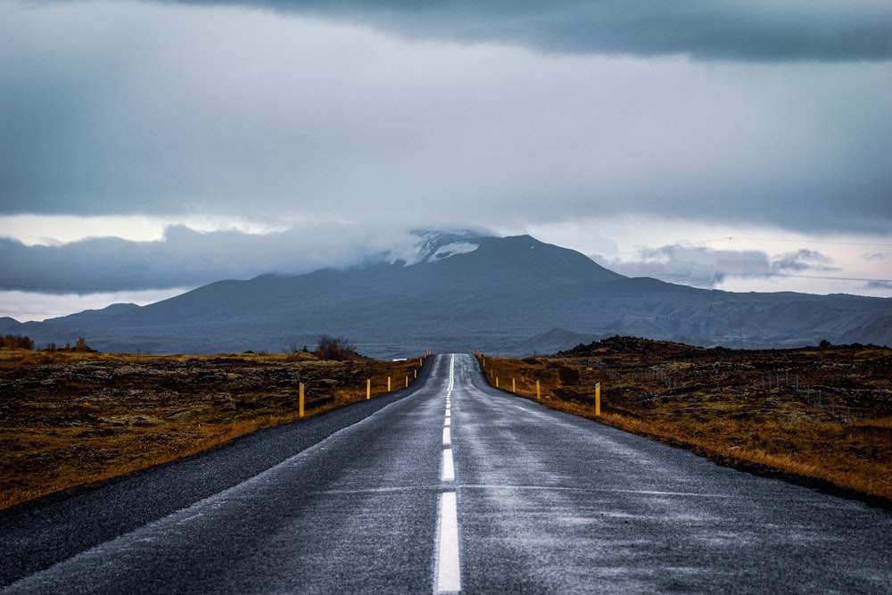 Carretera de hormigón gris cerca de la montaña bajo el cielo blanco durante el día