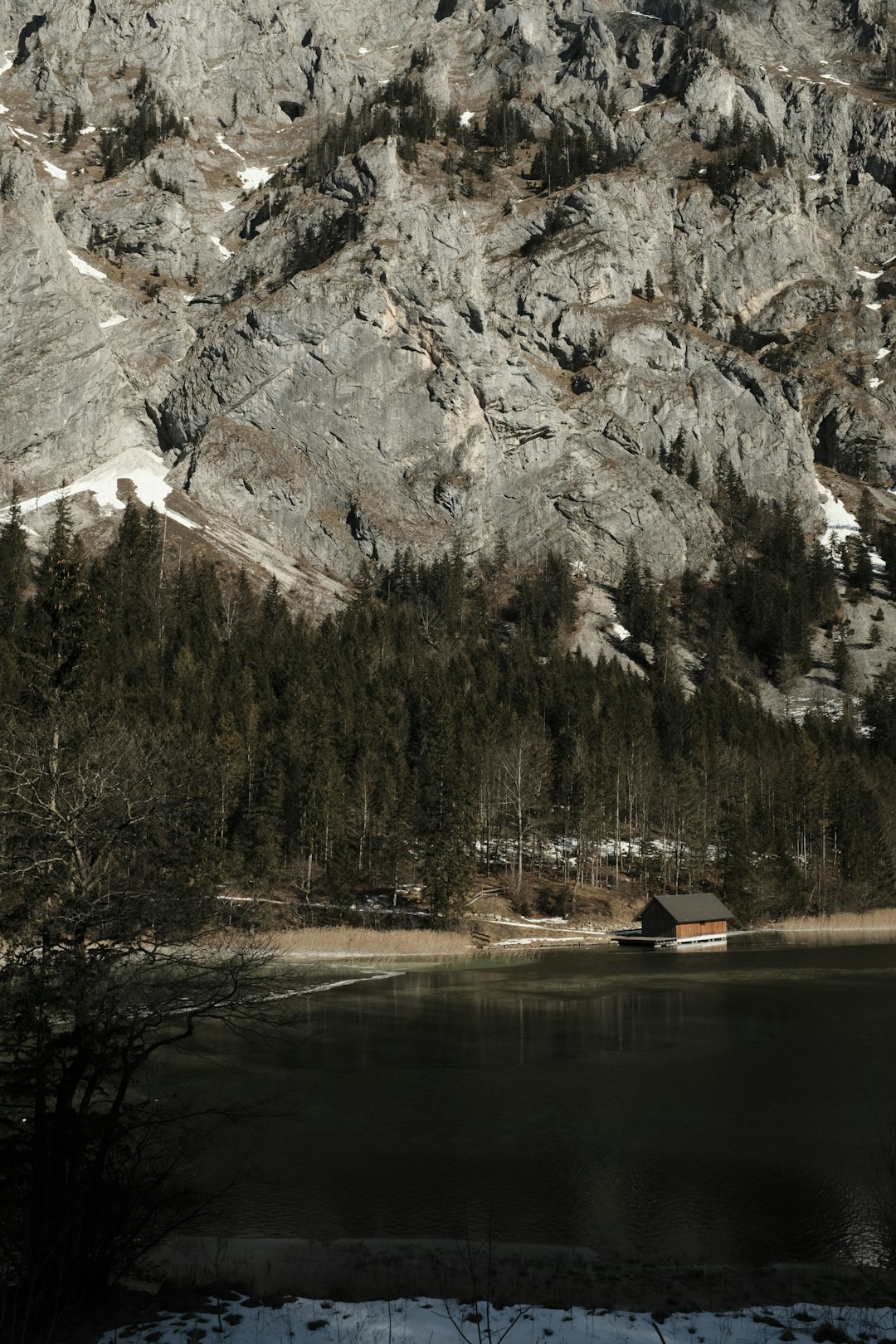 brown wooden house on lake near snow covered mountain during daytime