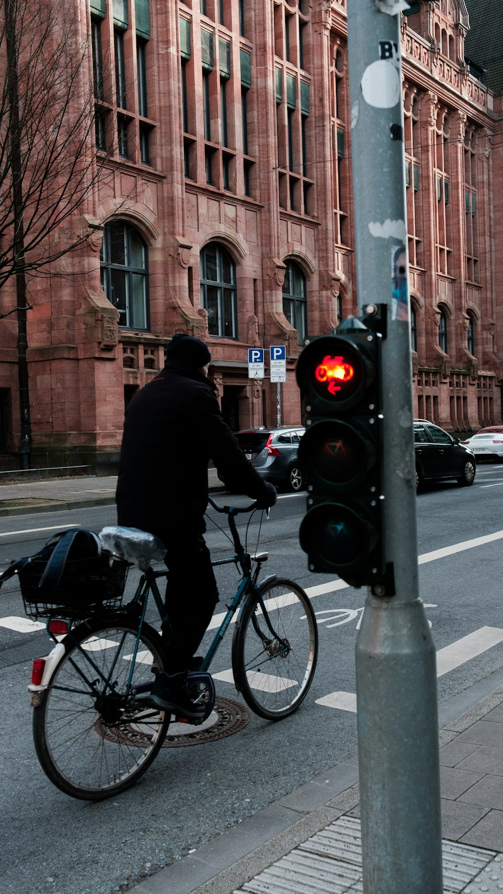 Mann in schwarzer Jacke fährt tagsüber Fahrrad auf der Straße