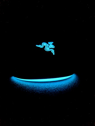 A neon blue logo resembling three intertwining snakes is set against a black background. Below, a softly glowing blue arc adds to the Futuristic vibe.