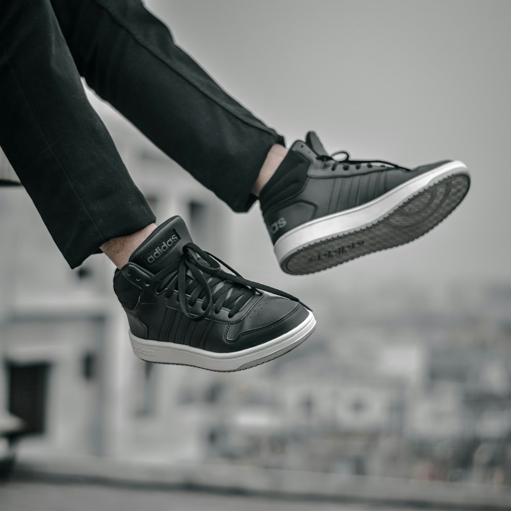 person in black pants wearing black and white nike sneakers