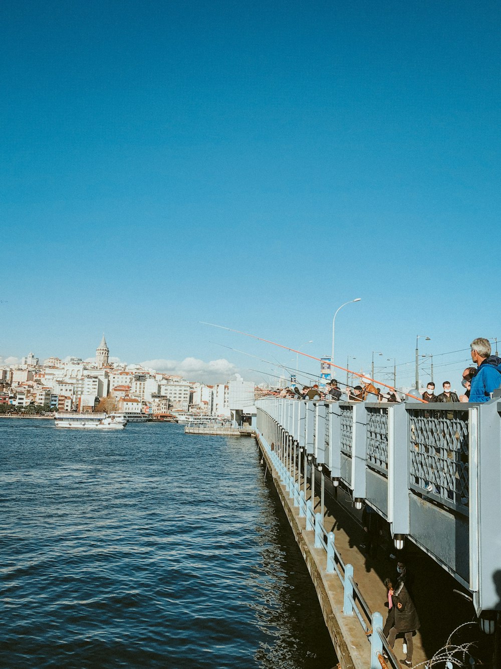 people on white and black bridge over blue sea during daytime