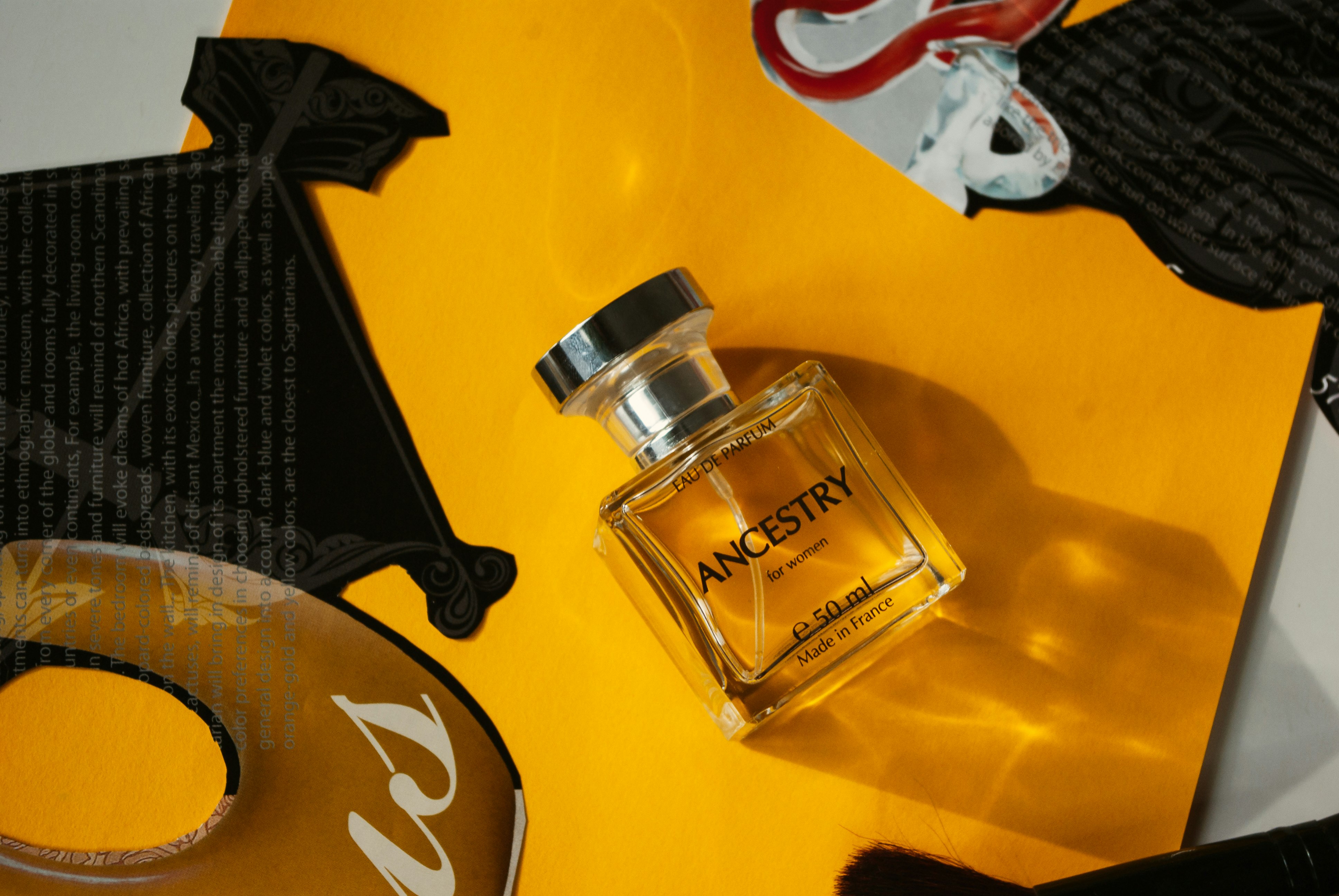clear glass perfume bottle on yellow surface