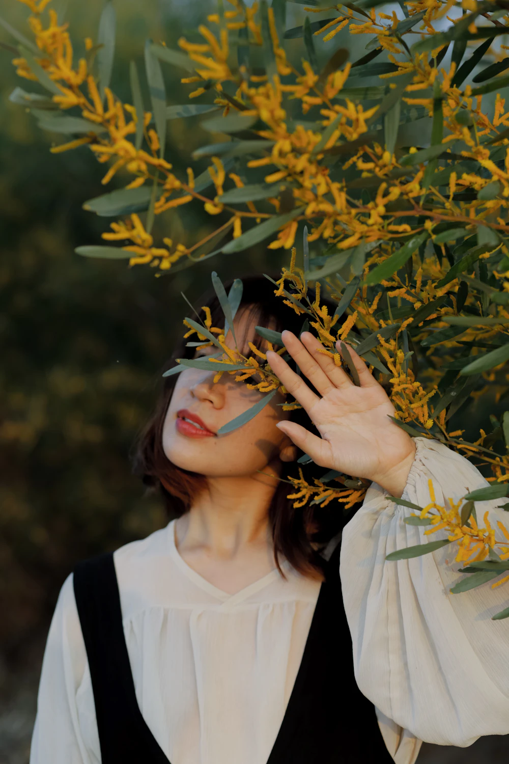 Mujer entre ramas de flores amarillas