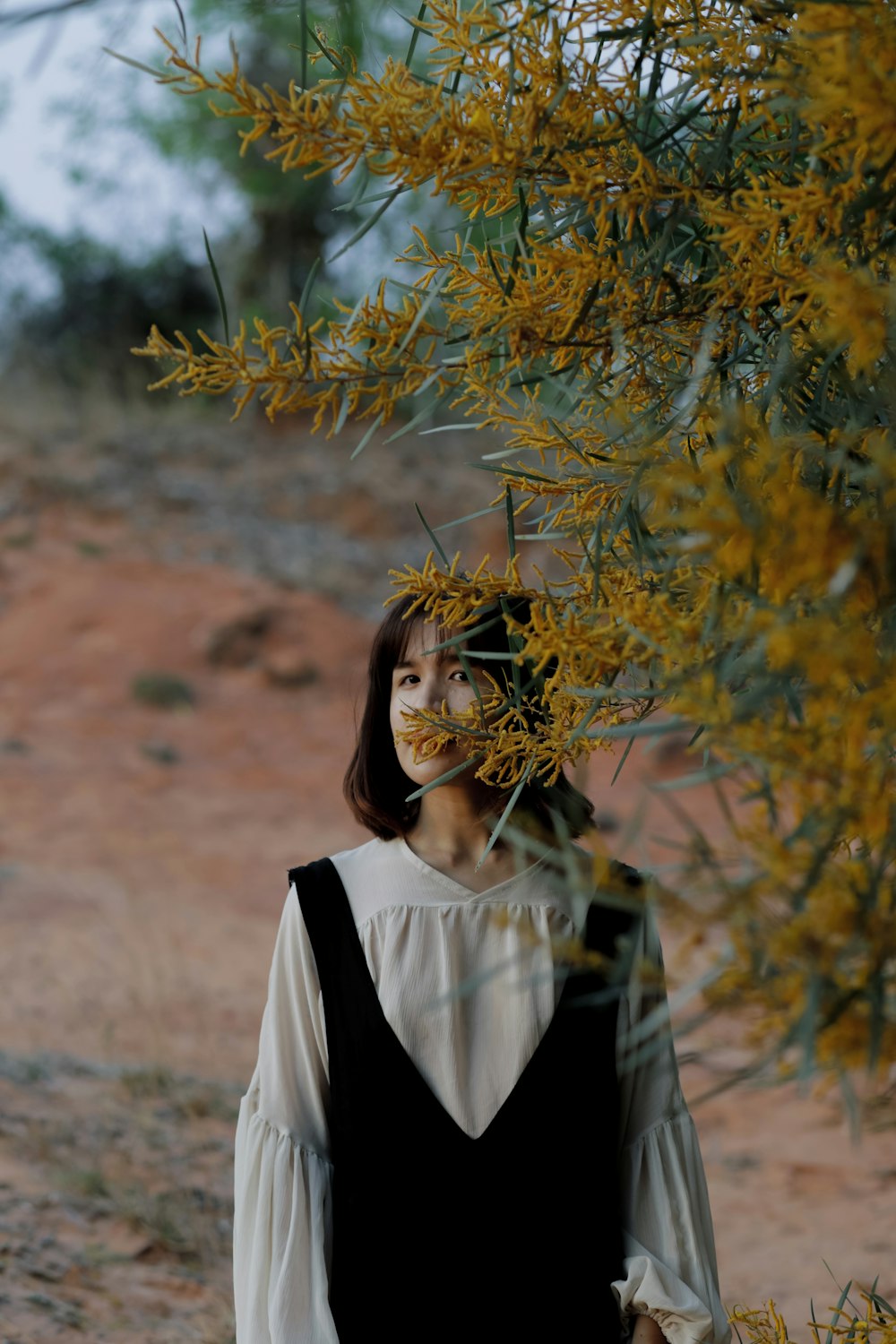 woman in black jacket standing near brown tree during daytime