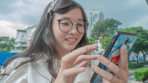 A happy young woman using her smartphone outdoors with a bright city background.