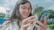 A smiling young woman using a mobile app to learn languages.