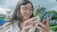 A happy woman using her phone to make an insurance payment.