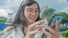 A confident young professional smiling while using a smartphone app in an urban setting.