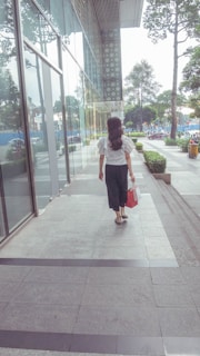 A modern woman carrying a minimalist cream-colored tote bag while walking through a park.