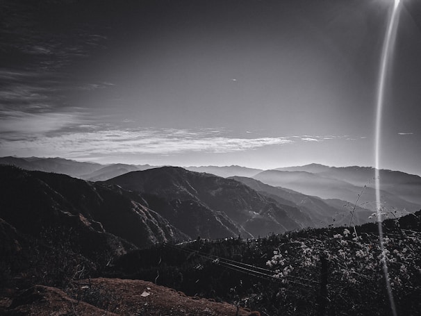 Serene landscape of misty morning hills captured in muted grayscale.