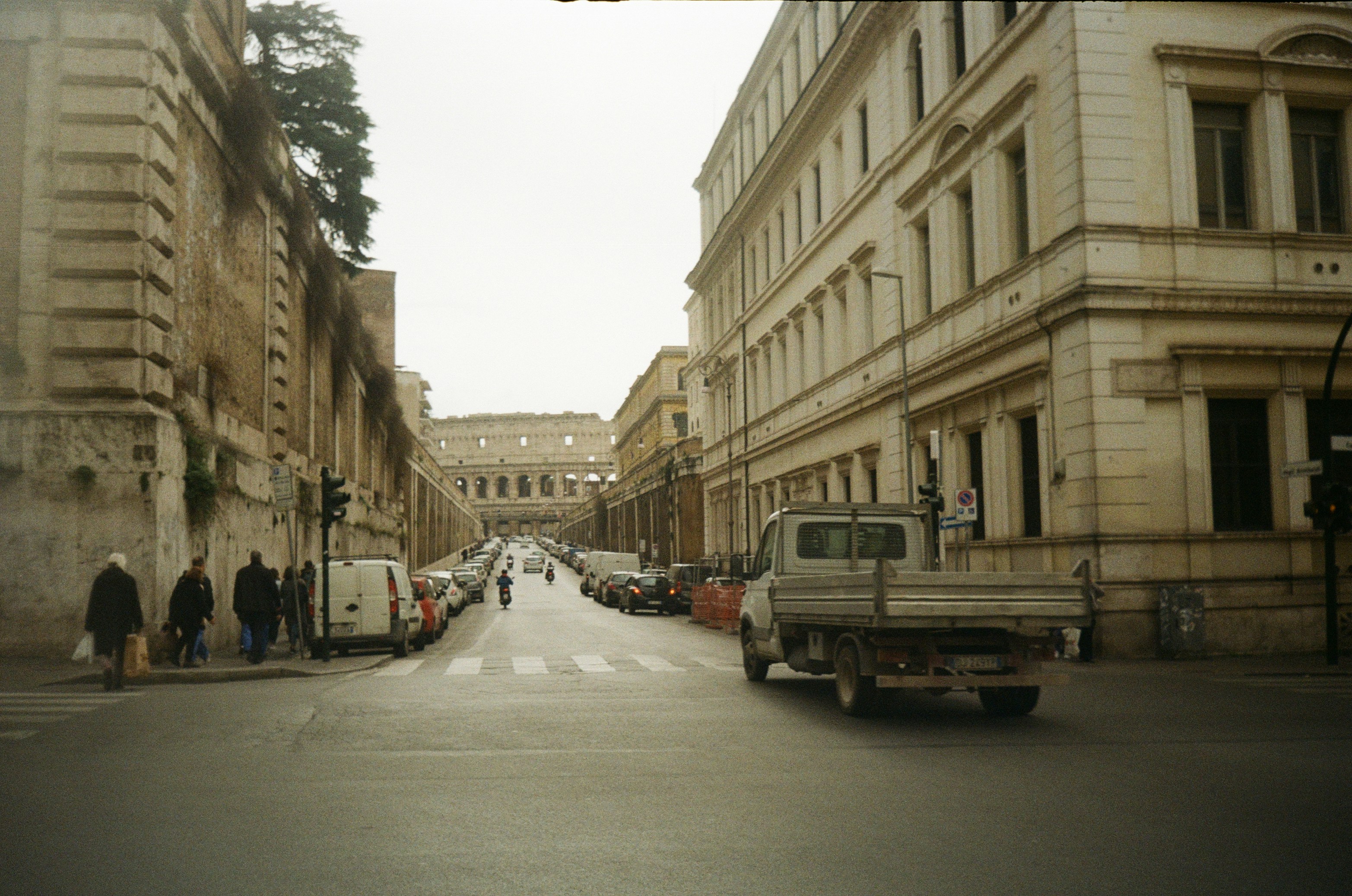 cars parked on side of the road in between buildings during daytime, 